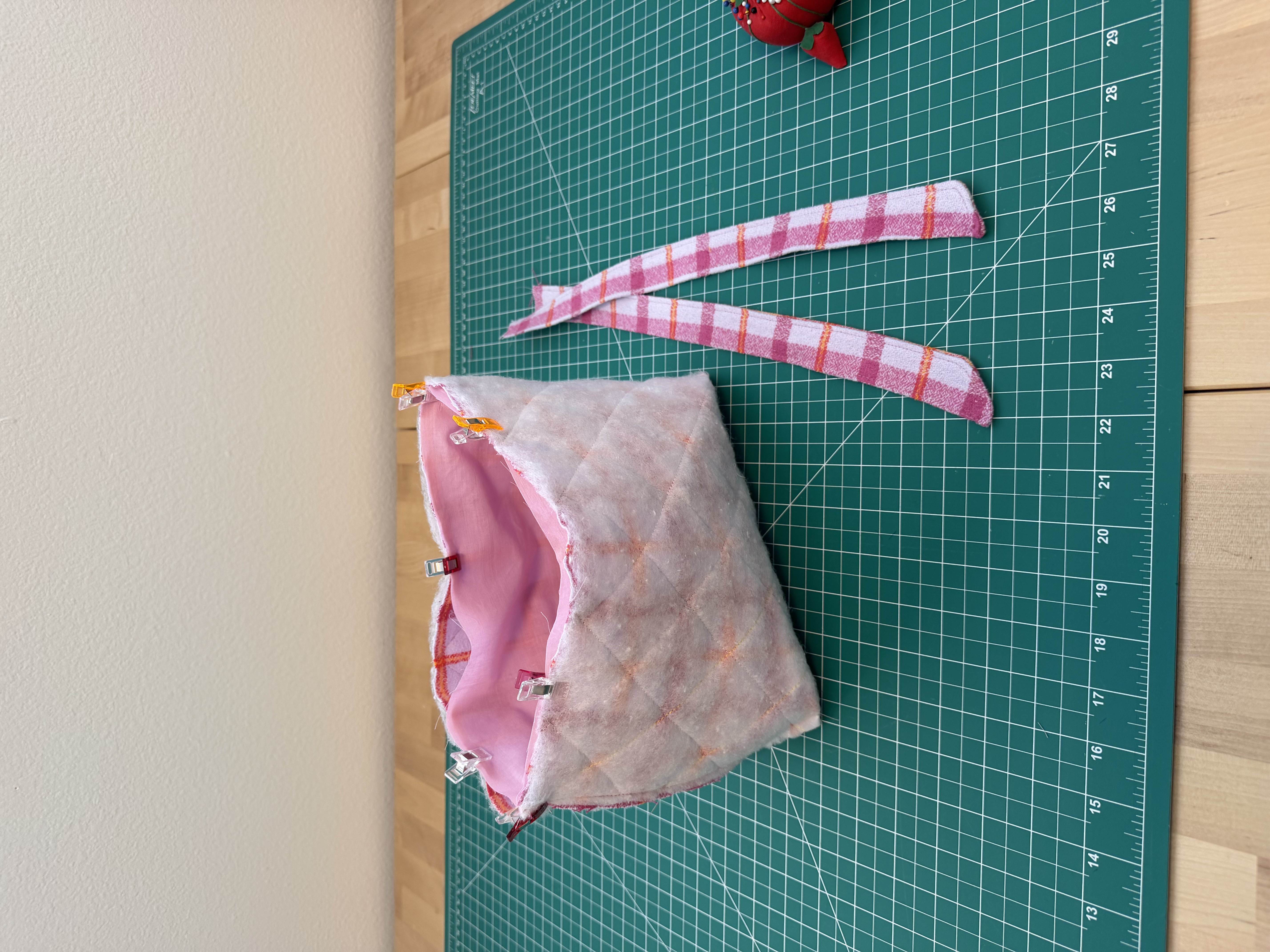 The sewn book sleeve clipped inside out on the cutting mat next to the cut plaid ties